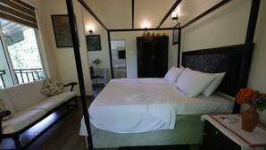 A bedroom with a large bed, a bench, a bedside table with a vase, and a view of the outside. - Sinharaja River Lodge (Kalawana)