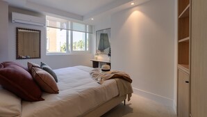 A bedroom with a large bed, a bedside table, a mirror, and a wardrobe.