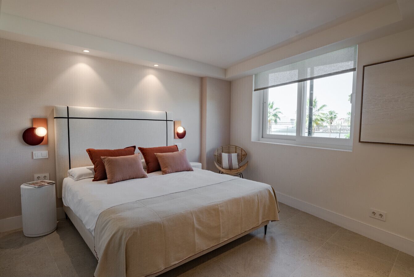 Quarto com uma cama grande, luminárias de cabeceira, janela com vista e uma obra de arte na parede.