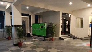 Un hall d’hôtel avec un distributeur automatique vert, des plantes en pot et un sol à carreaux.