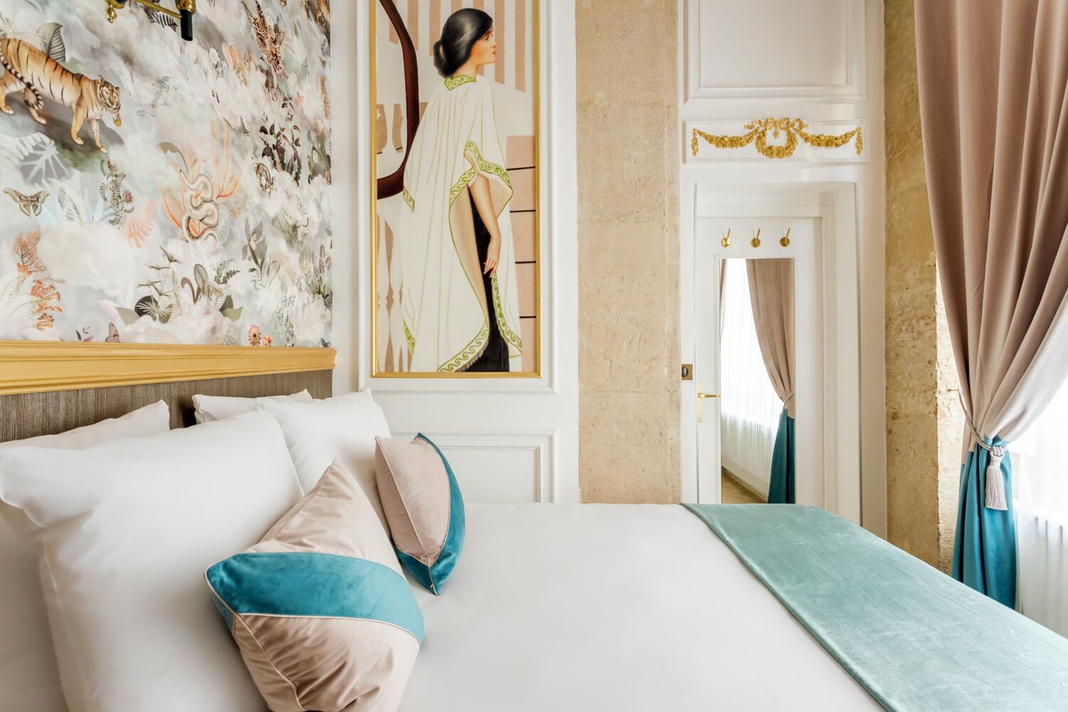 Ein Hotelzimmer mit einem großen Bett, einem Gemälde, einem Spiegel und Blick auf einen anderen Raum.