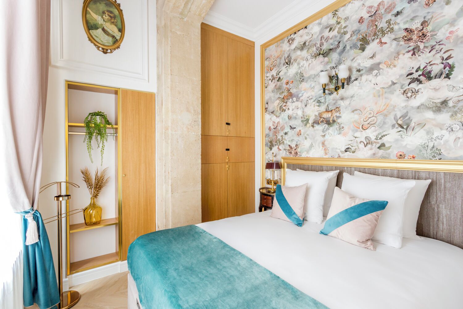 Une chambre d’hôtel avec un lit, une armoire, un miroir et un papier peint à motifs floraux.