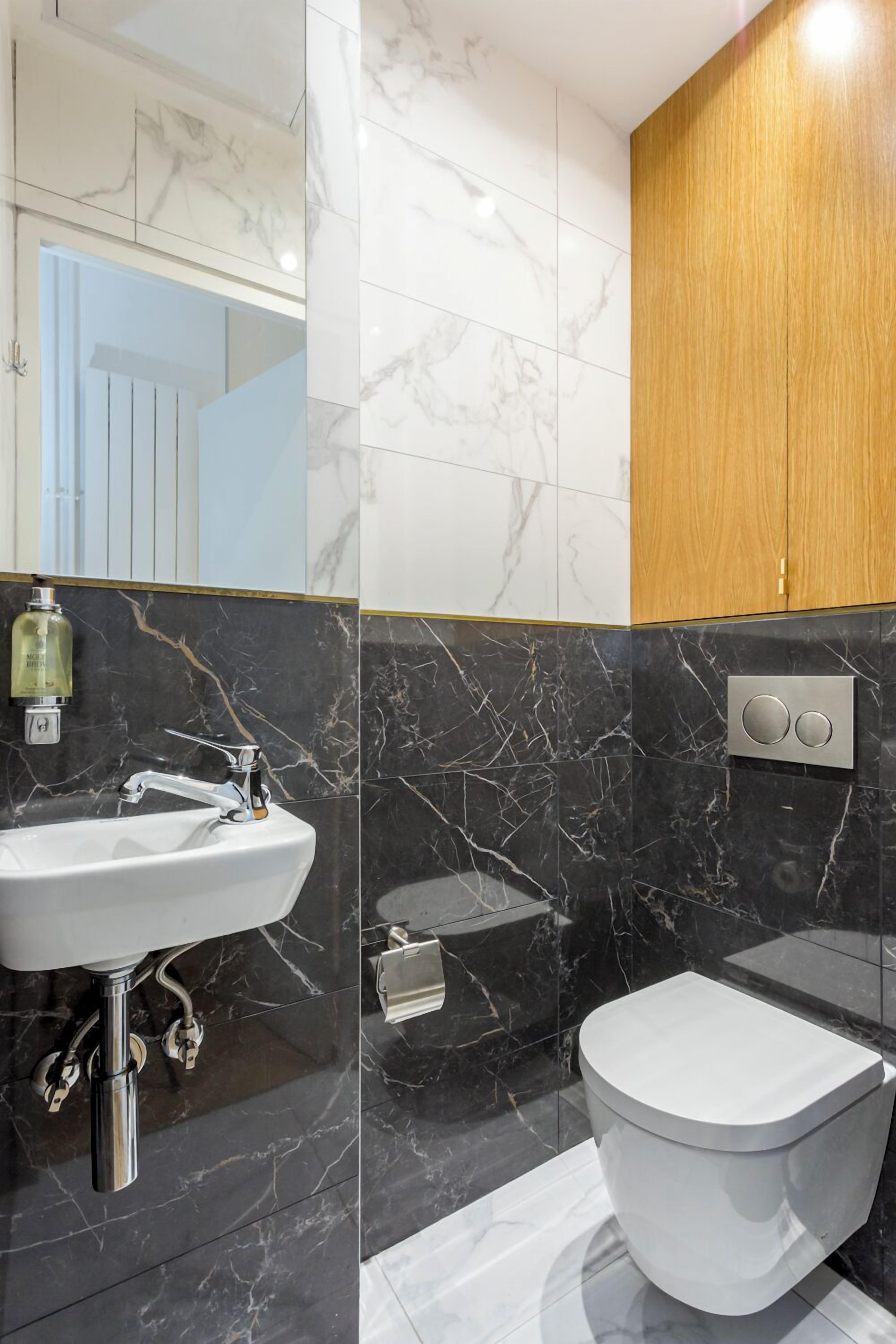 Une salle de bain moderne avec un lavabo en marbre, des toilettes et un meuble en bois.