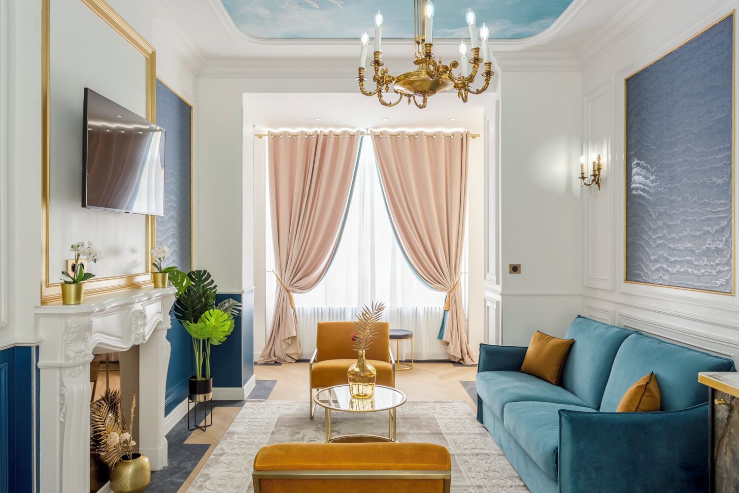 Una sala de estar con un sofá azul, una mesa de centro dorada y una chimenea.