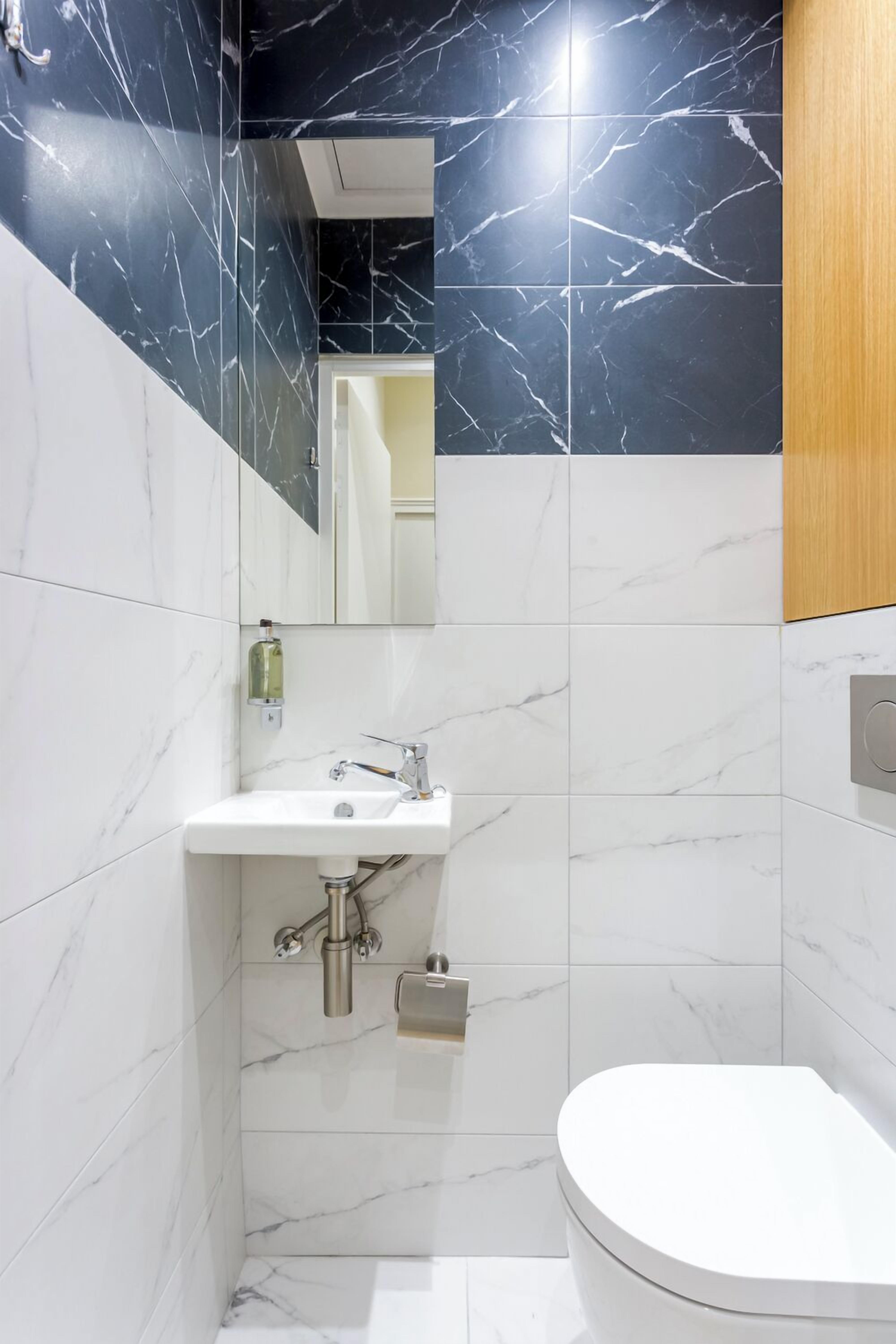 Un baño moderno con lavamanos, espejo y retrete blancos.