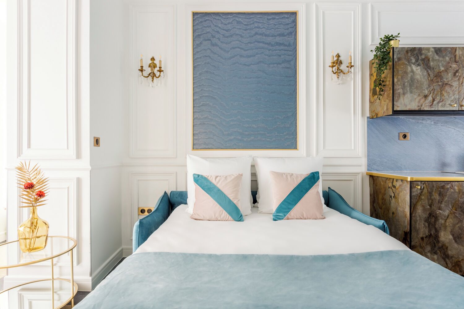 Een slaapkamer met een bed, een schilderij aan de muur en een marmeren kast.
