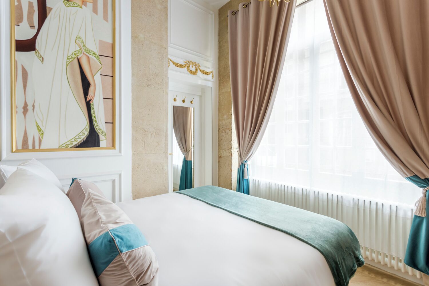 A hotel room with a large bed, a painting on the wall, and curtains on the windows.