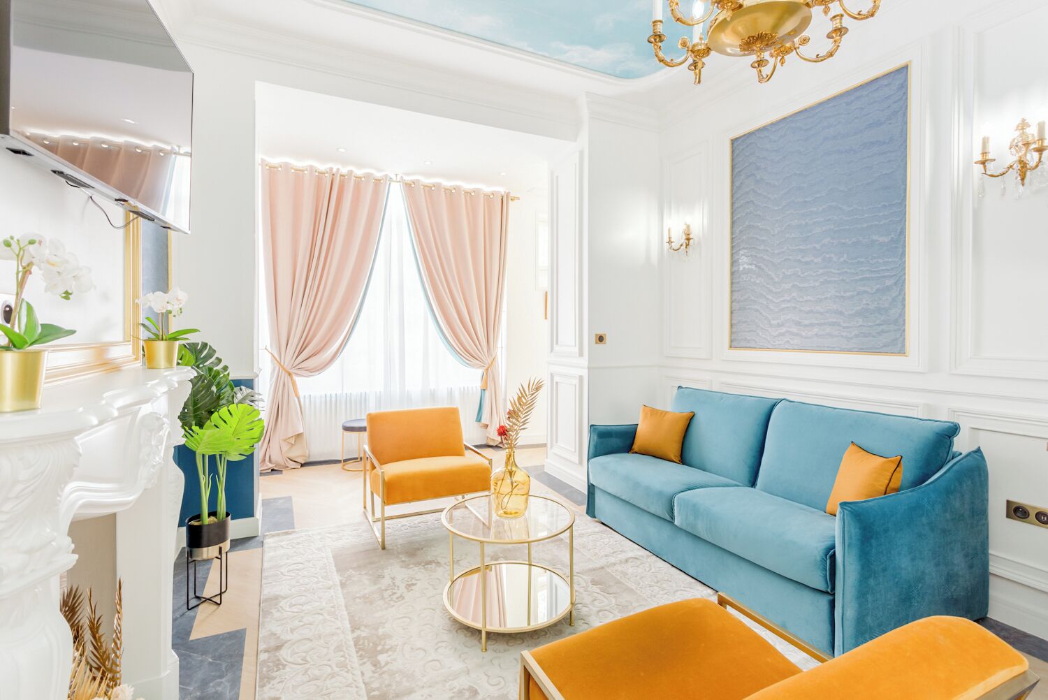A modern living room with a blue sofa, orange chairs, a glass coffee table, and a fireplace.