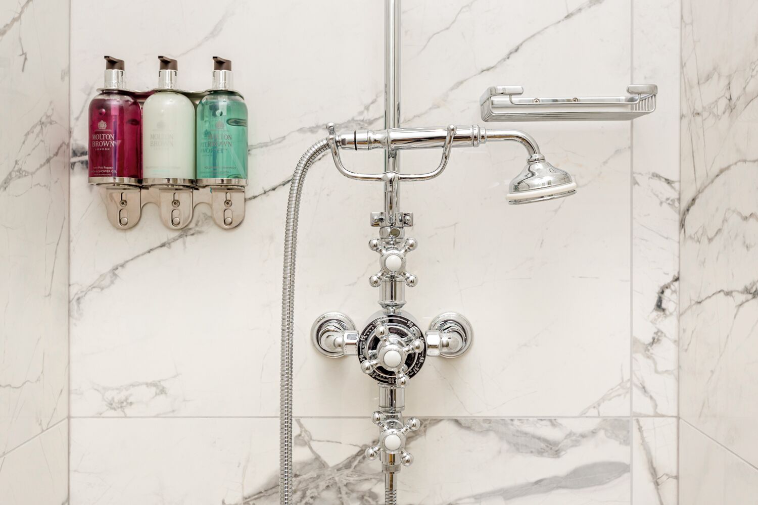 Une salle de bain équipée d’une douche, d’un pommeau de douche et d’un distributeur de savon mural.