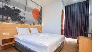 A hotel room with a bed, wooden headboard, and a mural on the wall. - Seaside Sayang Heulang by Sinergi (Pameungpeuk)