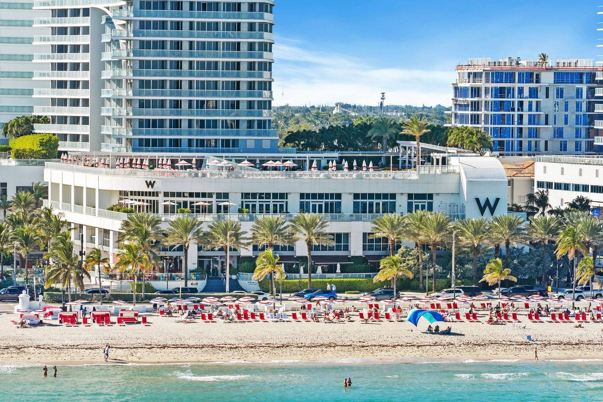 A beachfront hotel with multiple floors, a prominent 'W' sign, and a beach area with sun loungers and umbrellas.