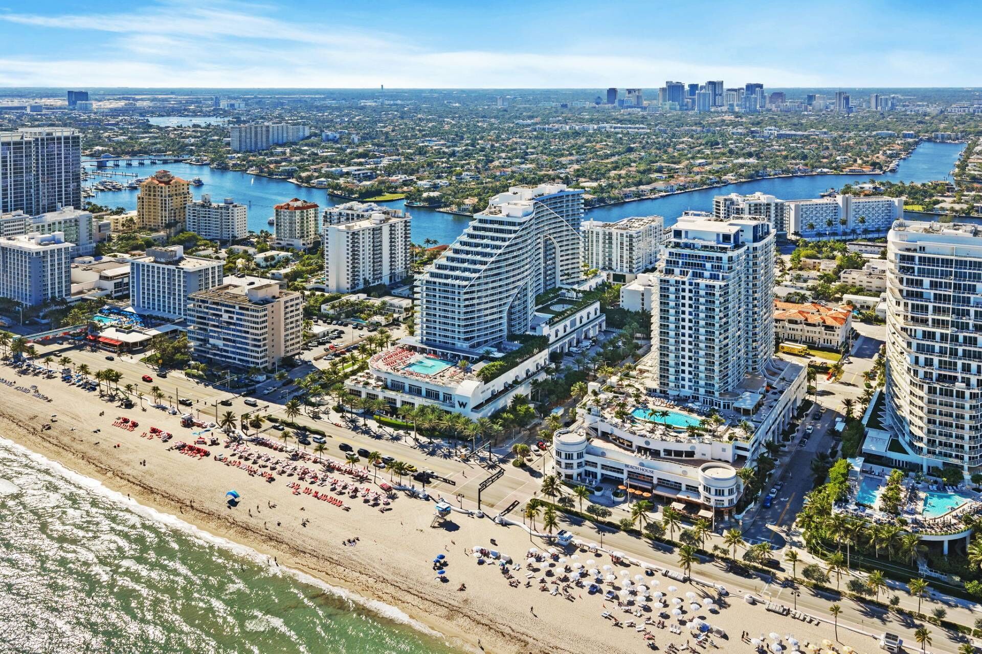 A coastal cityscape with high-rise hotels, a beach, and a marina.