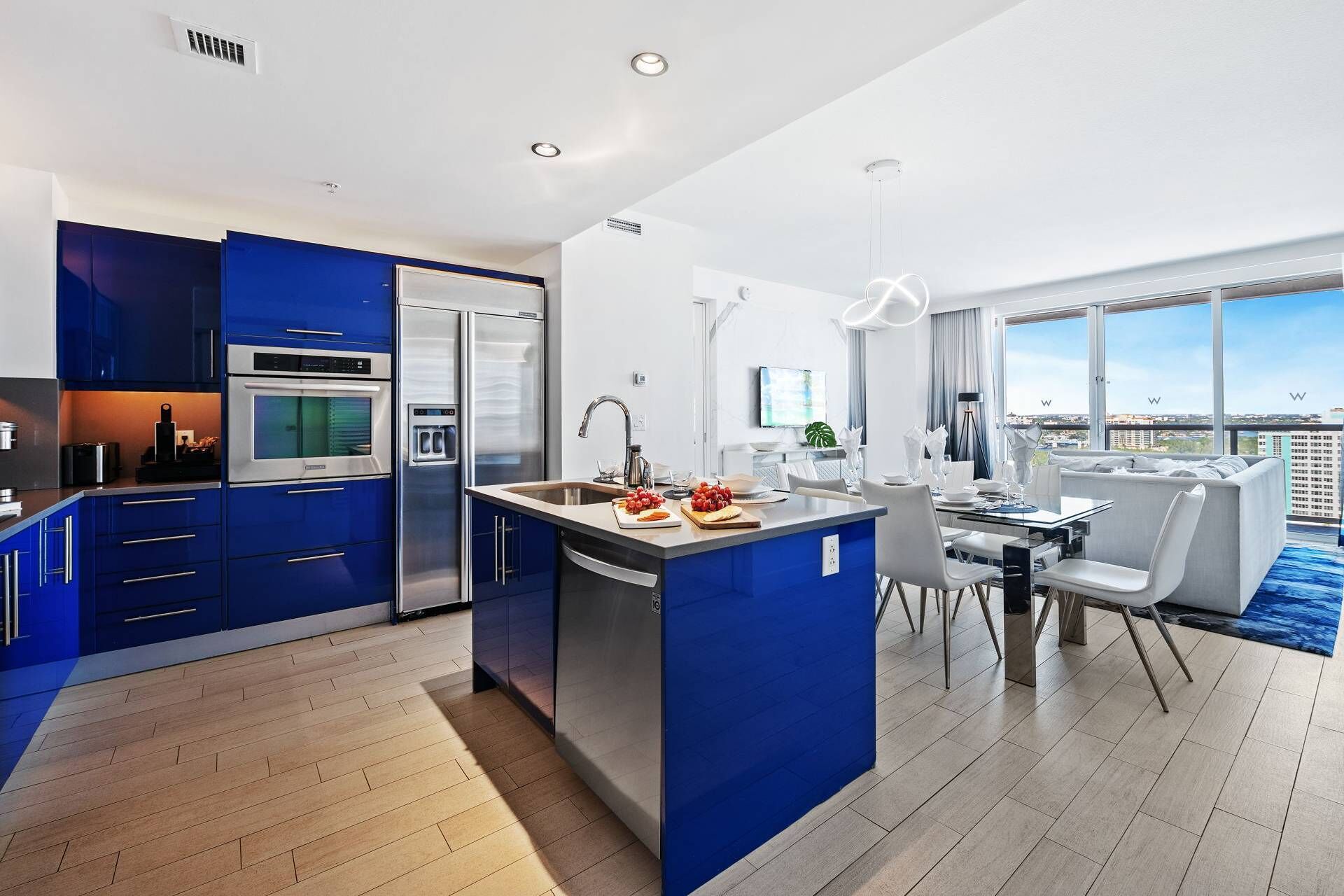 A modern kitchen with blue cabinets, a built-in oven, and a refrigerator.