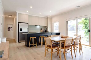 A modern kitchen with a central island, wooden chairs, and a dining table.