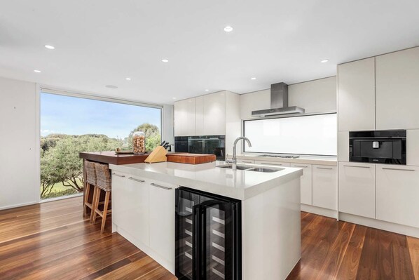 A modern kitchen with a large island, built-in appliances, and a view of the outdoors.