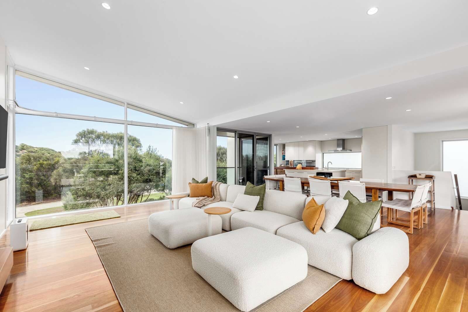 A modern living room with a sectional sofa, a dining area, and a kitchen.