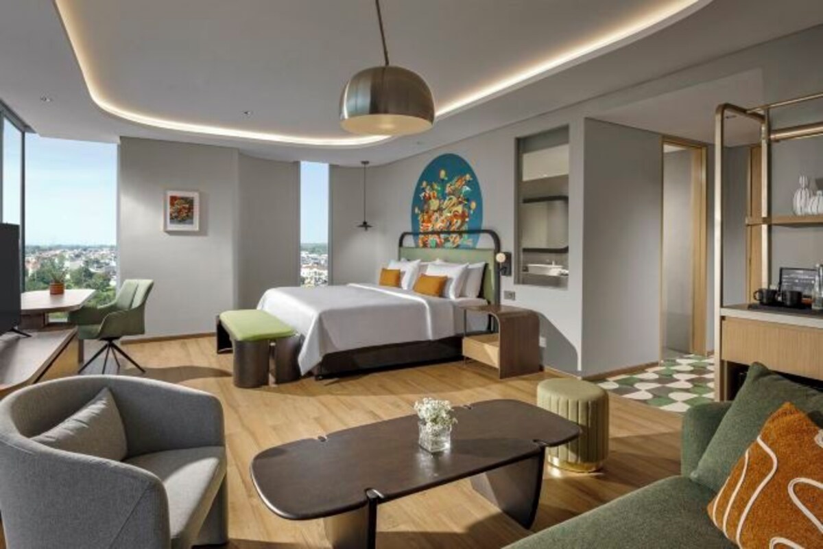 Een moderne hotelkamer met een groot bed, een bureau, een zithoek en uitzicht op de stad.