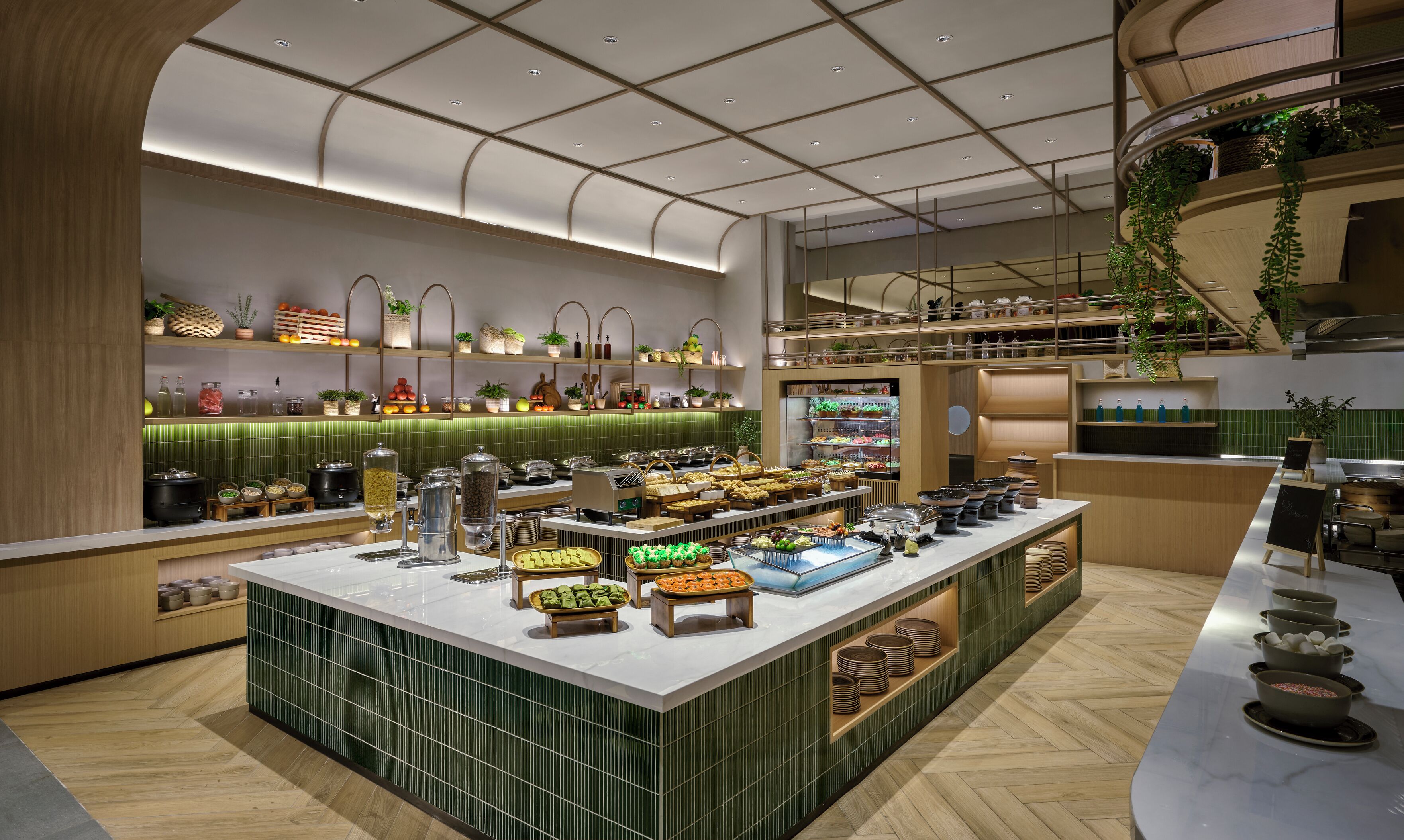 A modern buffet setup with various food items and drinks, a green-tiled backsplash, and a wooden floor.
