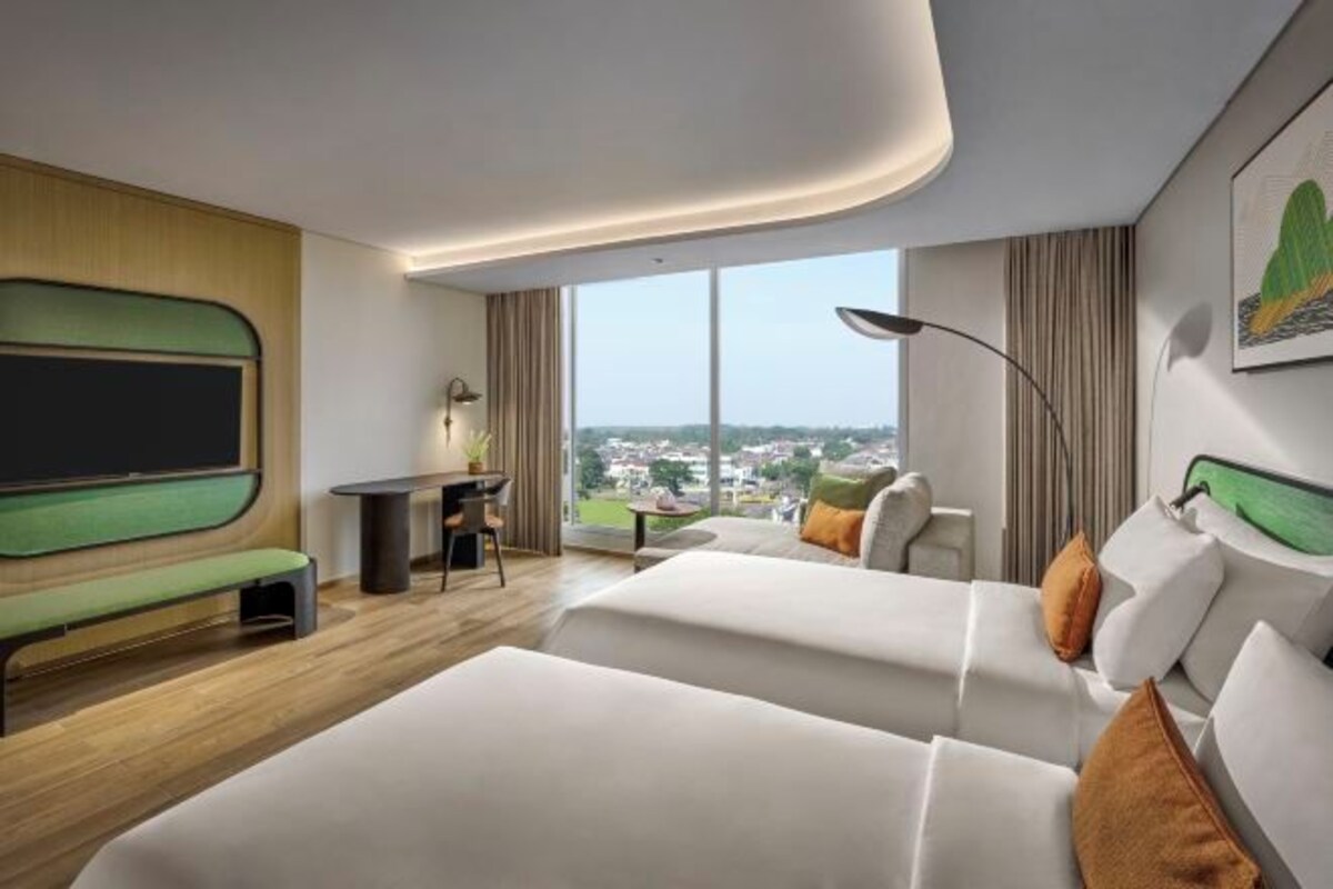 Een moderne hotelkamer met een groot bed, een bureau en uitzicht over de stad.