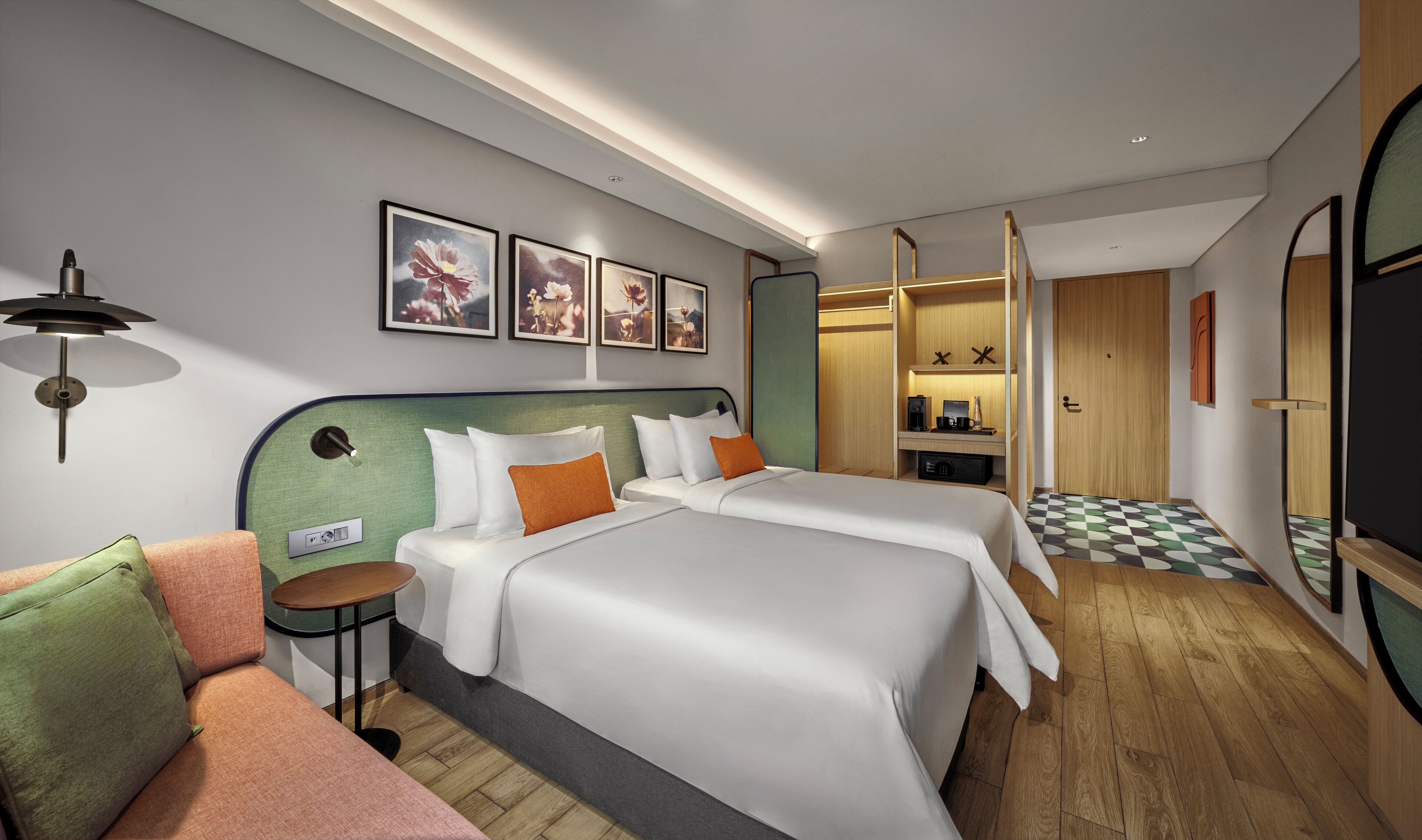 Quarto de hotel com duas camas, um sofá, uma escrivaninha e um banheiro.