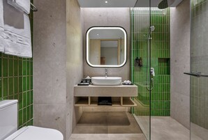 Un baño moderno con un lavamanos independiente, un espejo grande y una cabina de ducha.
