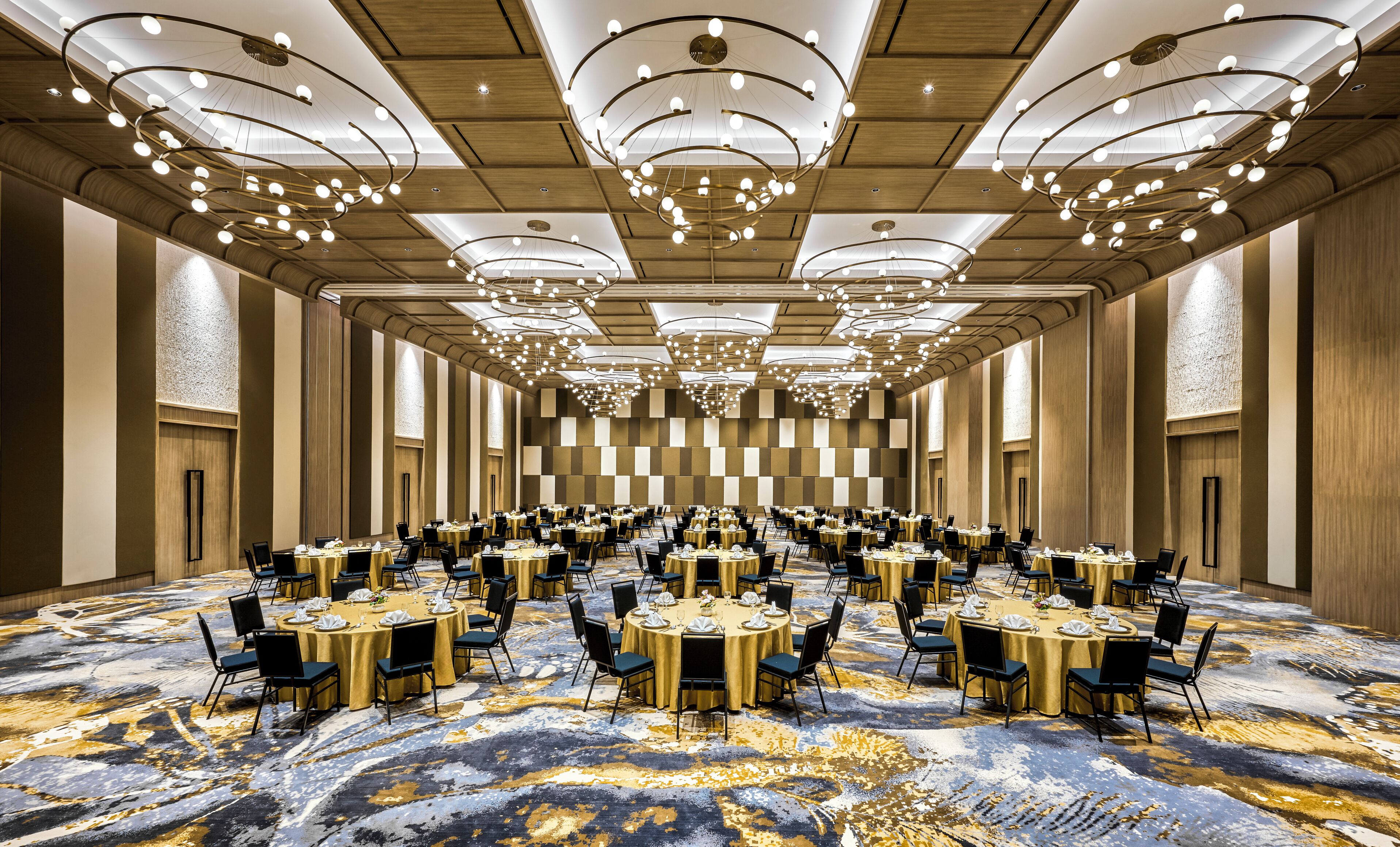 A large conference room with multiple round tables, black chairs, and a patterned carpet.