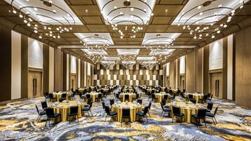 A large conference room with multiple round tables, black chairs, and a patterned carpet.