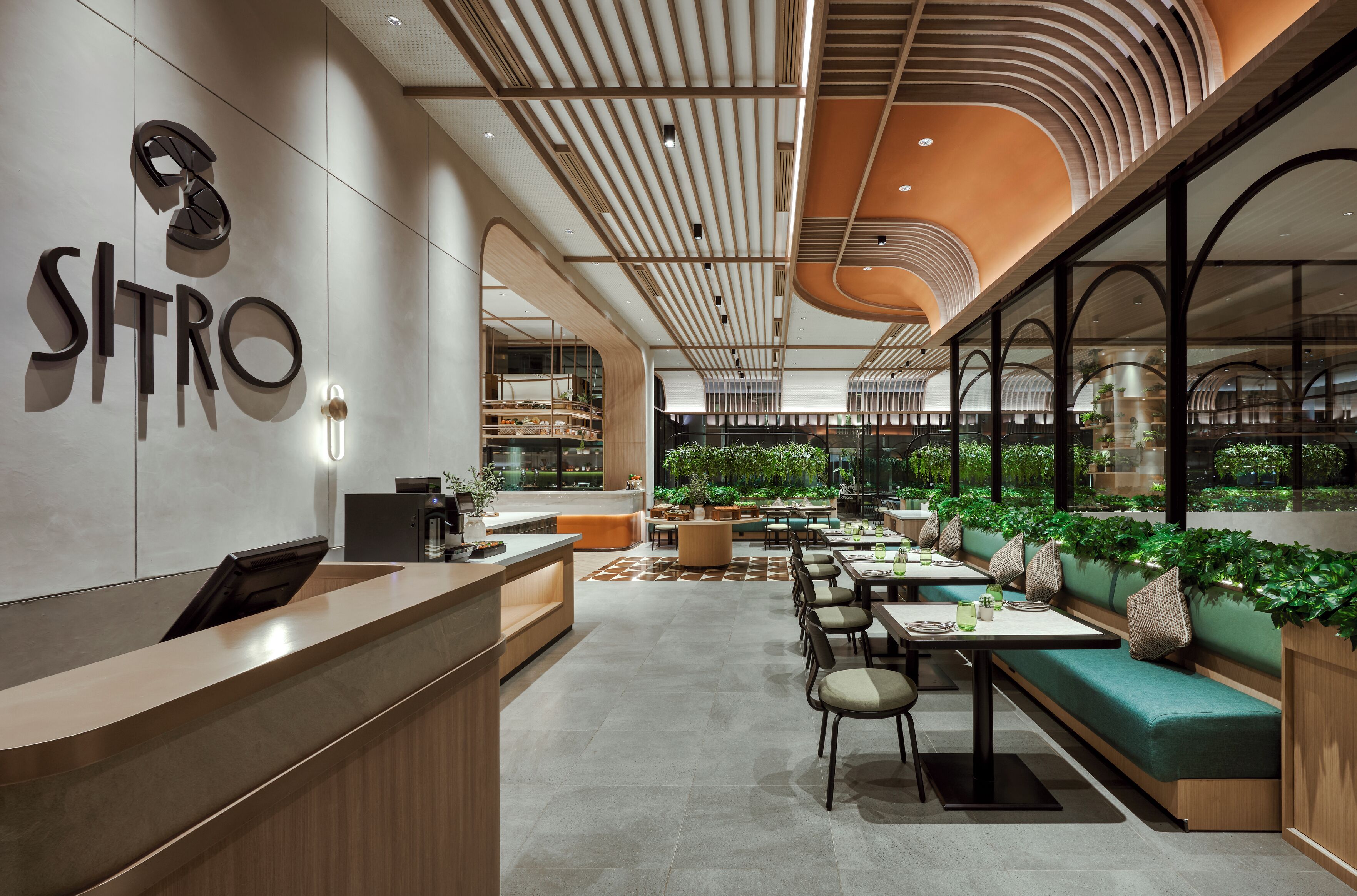 Un intérieur moderne comprenant un comptoir d’accueil, des espaces d’attente et une vue sur un jardin intérieur.