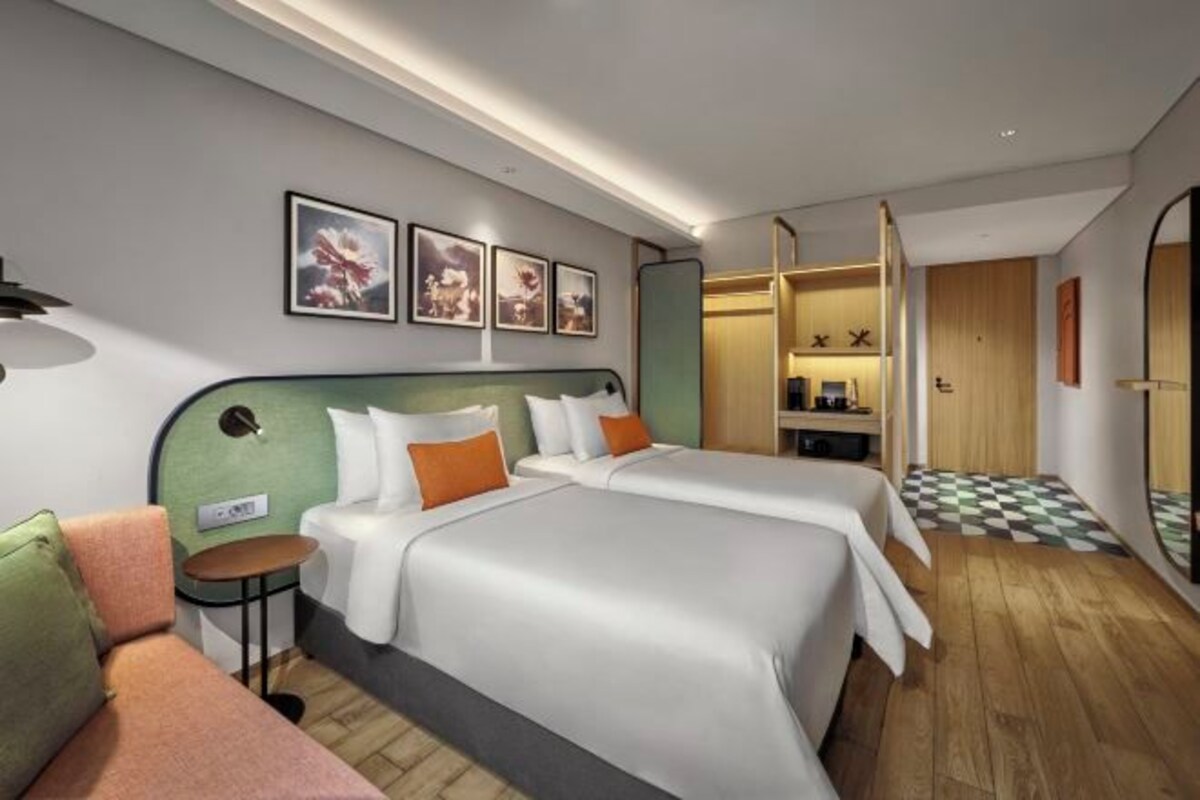Een moderne hotelkamer met twee bedden, een klein tafeltje en kunst aan de muur.