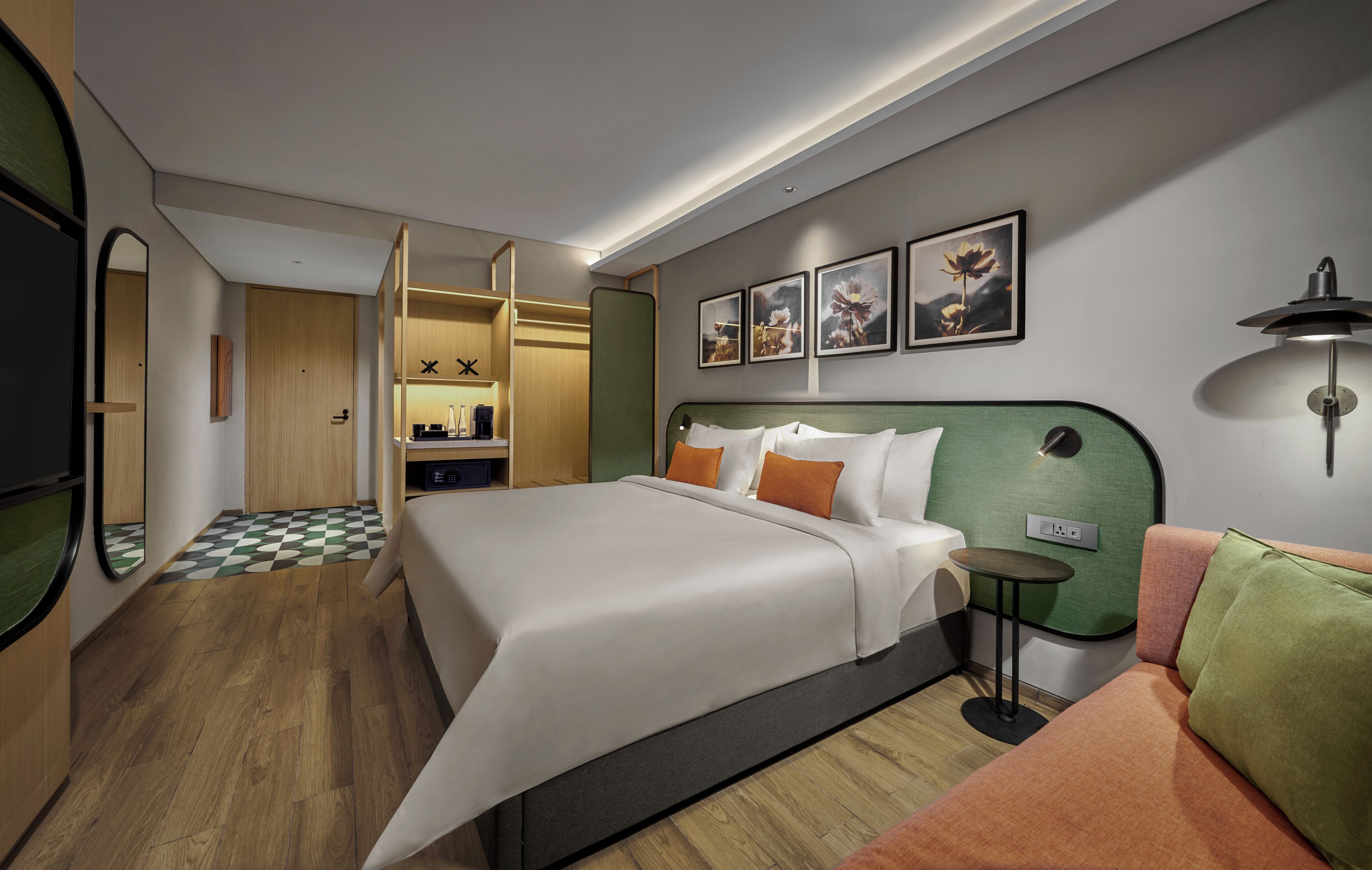 Una habitación de hotel moderna con una cama grande, una mesita pequeña, un sofá y un vestidor.