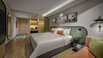 Una habitación de hotel moderna con una cama grande, una mesita pequeña, un sofá y un vestidor.