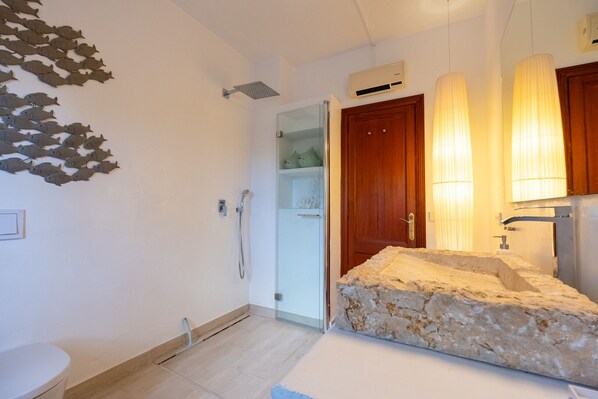 Une salle de bain avec un lavabo en pierre, une porte en bois et une douche.