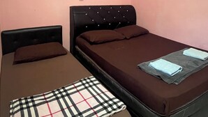 Una habitación con dos camas, una lámpara en la pared y un cuadro pequeño.