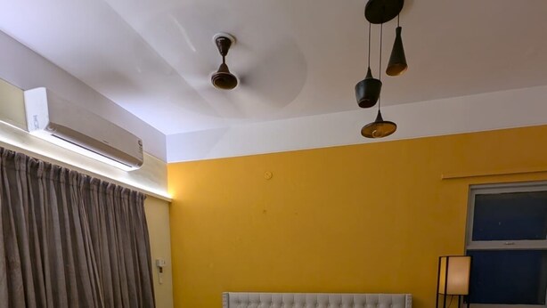A hotel room with a large bed, a bench, a standing lamp, and a ceiling fan.