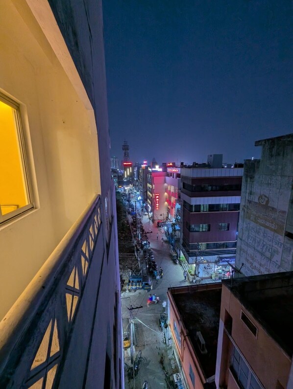 A nighttime cityscape with buildings, streetlights, and a few pedestrians.