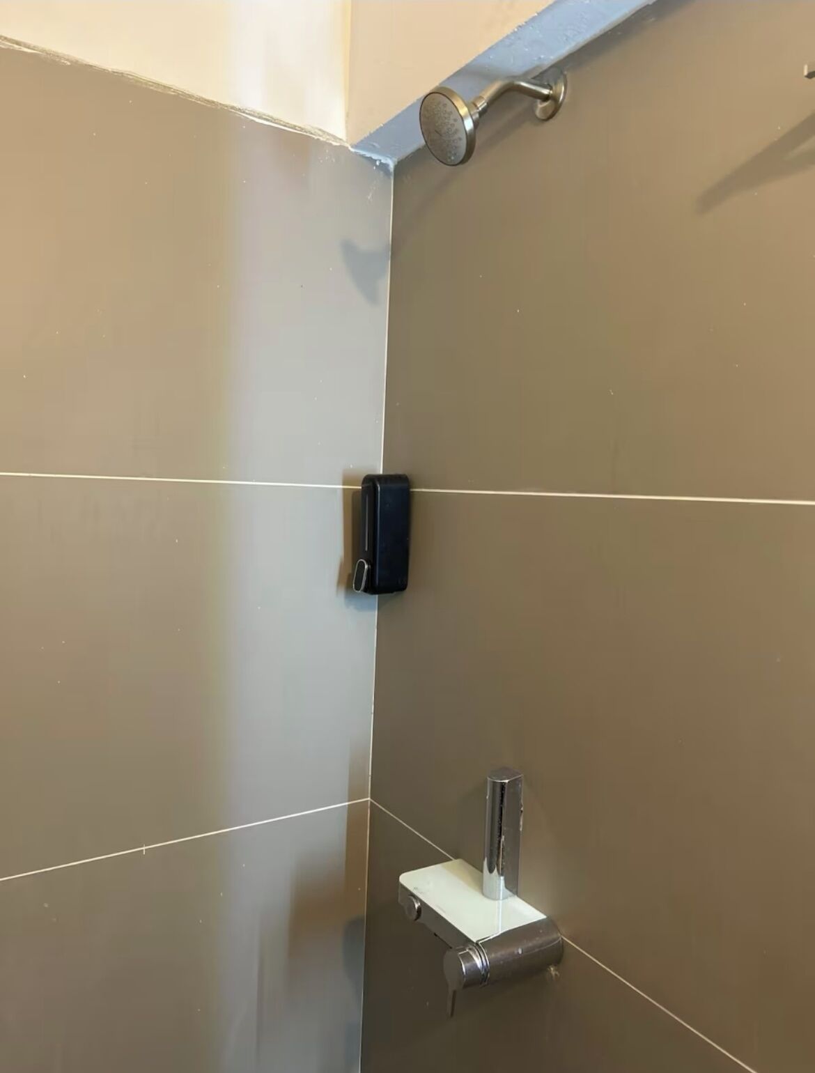 A bathroom with a shower, a hand dryer, and a towel rack.
