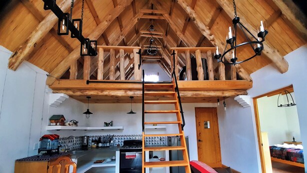 A spacious loft-style room with a wooden staircase leading to an upper level. - El Colibri Cabin (San Juan La Laguna)