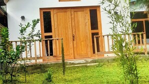 A two-story house with a wooden front door, large windows, and a small porch. - El Colibri Cabin (San Juan La Laguna)