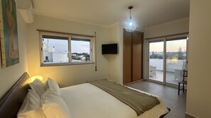Une chambre à coucher avec un lit, une télévision et un balcon équipé d’une chaise.