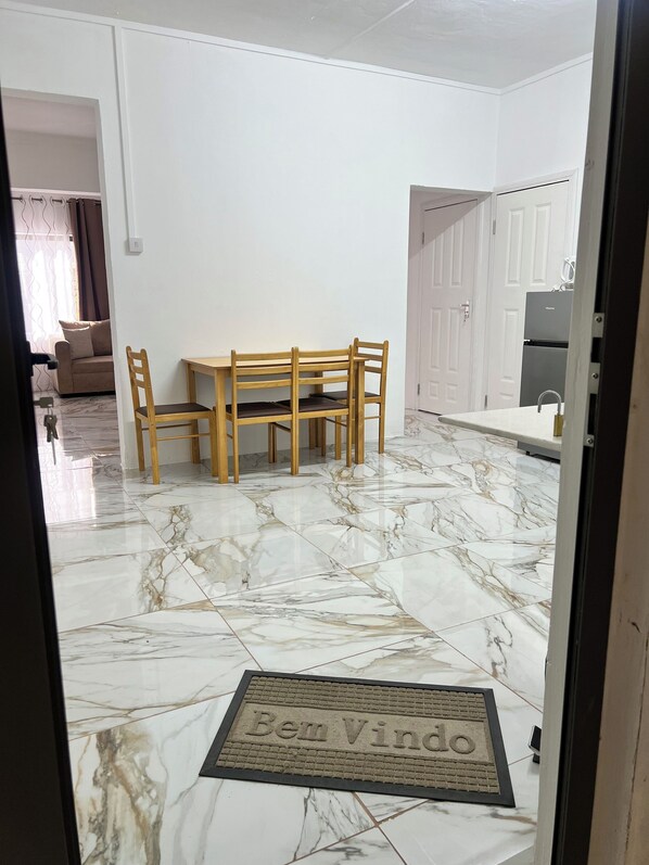 Una cocina con suelo de mármol, una mesa de comedor con sillas, un refrigerador y un lavabo.