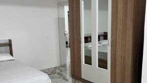Ein Schlafzimmer mit Bett, Holzschrank und Marmorboden.