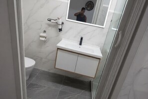 Un baño con lavamanos, espejo y retrete blancos.