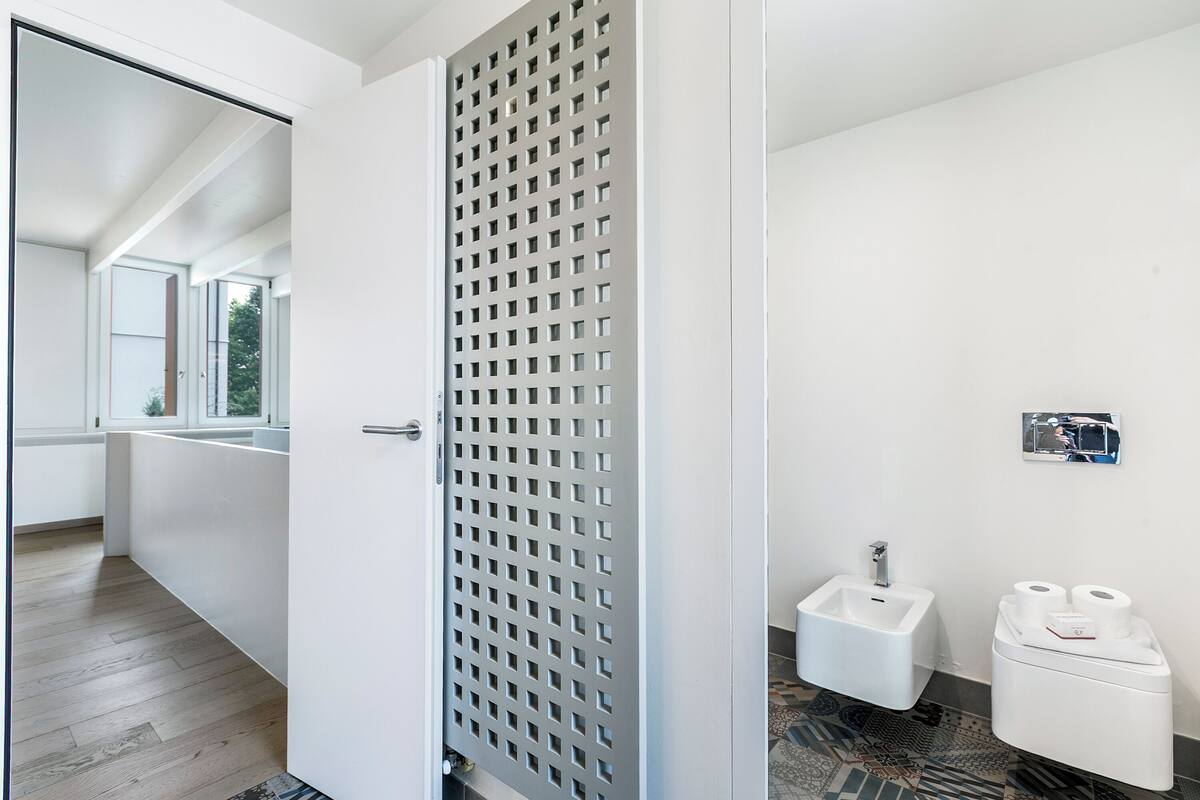 A modern bathroom with a bidet, toilet paper, and a mirror.