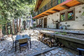Un patio in pietra con tavolo e sedie, un barbecue e un pontile in legno con ringhiera.