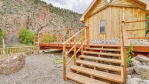 A wooden cabin with a stone foundation, wooden stairs, and a wooden deck. - Creekside Cabin w/ Deck & Views in Panguitch! (Panguitch)