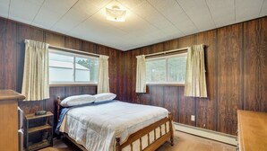 A bedroom with a wooden bed, two windows with curtains, a nightstand, and a dresser. - Fisher's Retreat: Hayward Home, Near ATV Trails! (Hayward)