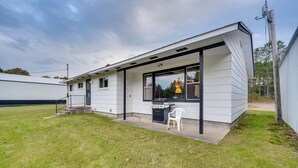 A single-story house with a covered porch, a grill, and a chair. - Fisher's Retreat: Hayward Home, Near ATV Trails! (Hayward)