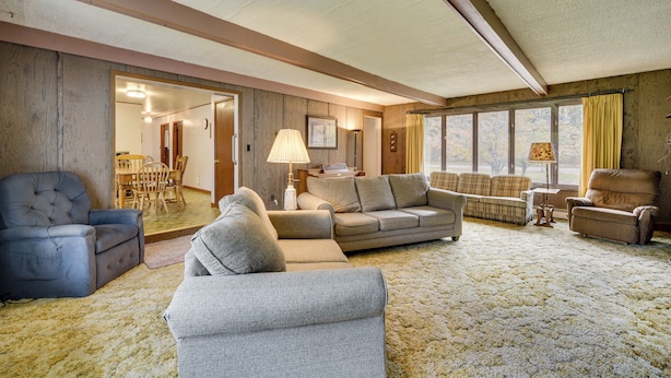 A spacious living room with a large sofa, armchairs, and a dining area visible through an open doorway. - Fisher's Retreat: Hayward Home, Near ATV Trails! (Hayward)