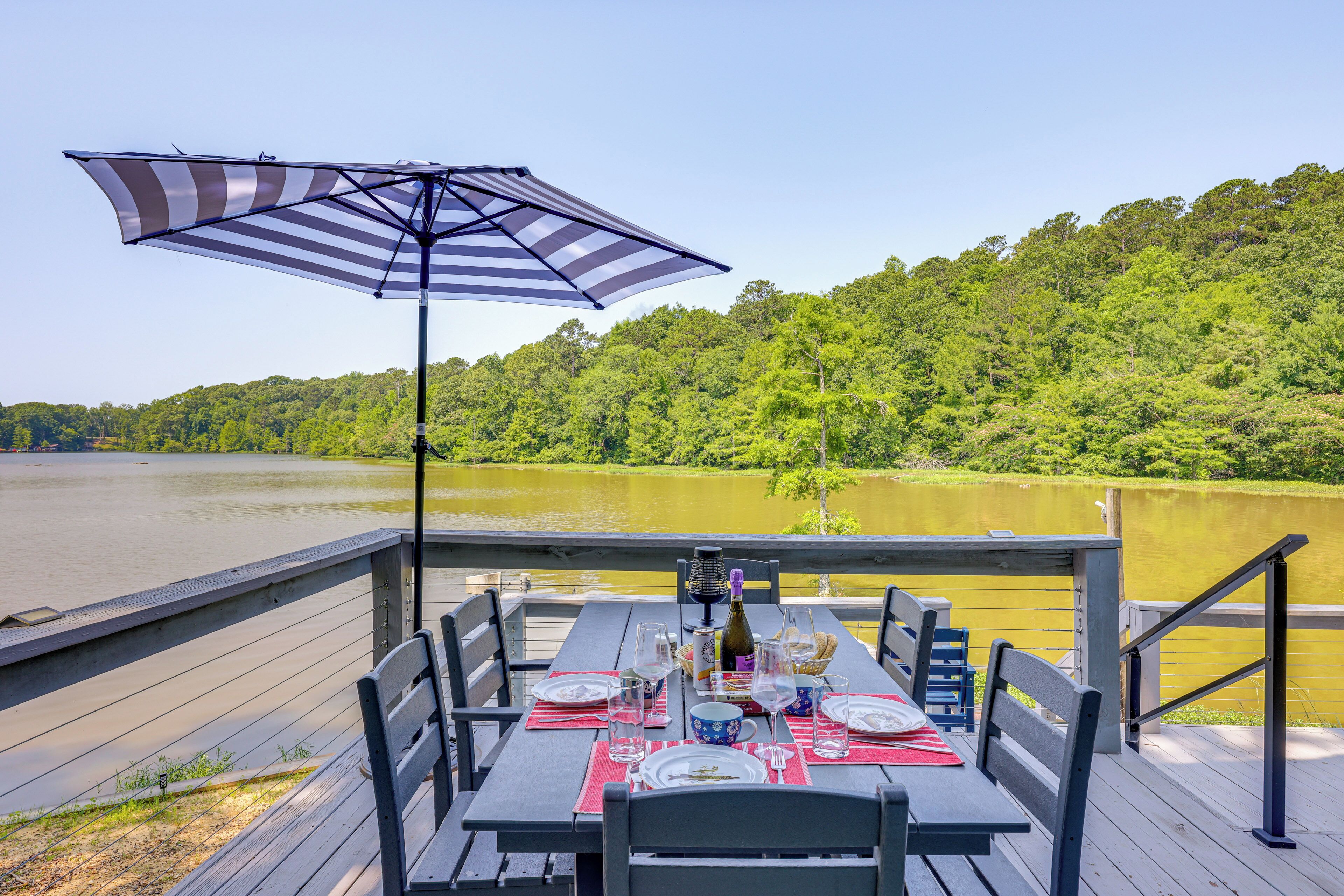 Una mesa de comedor en una terraza con vistas a un lago y un bosque.
