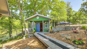 Une petite maison verte avec un porche, un chemin menant à la maison et une voiture garée à proximité.